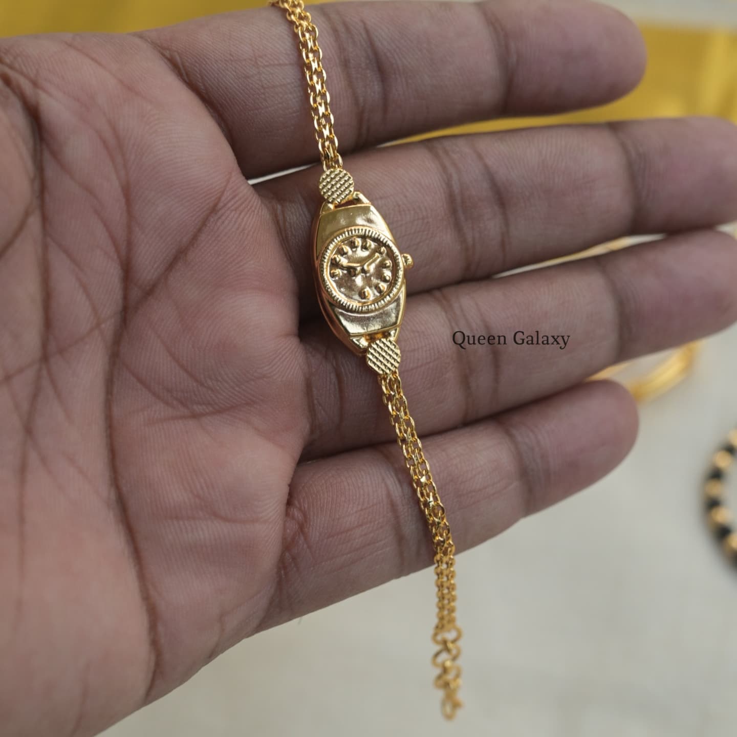 1 gram gold plated baby bracelet displayed on a person's hand, featuring a small watch head and a chain-link bracelet.
