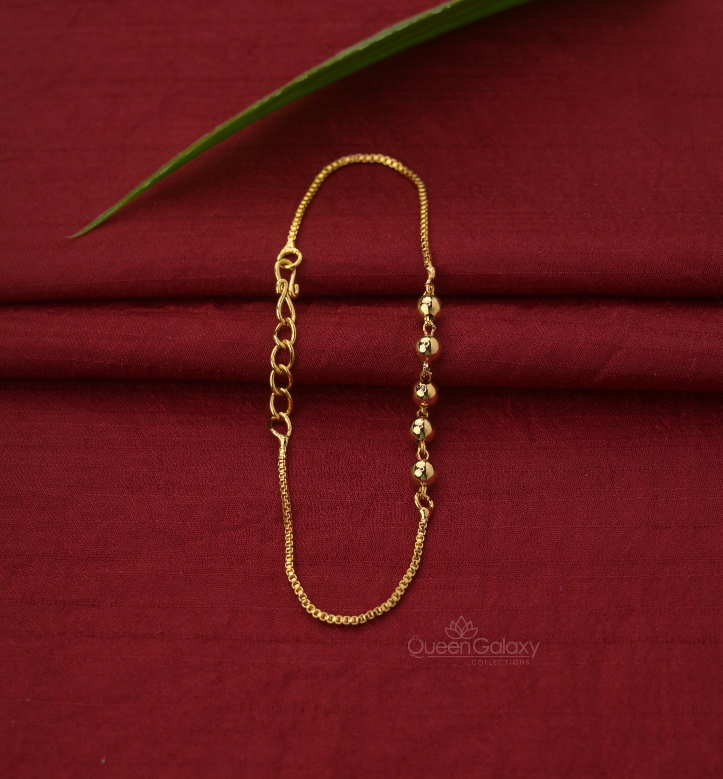 Gold Plated Beaded Chain Bracelet laid out on a red fabric surface. queen galaxy collection