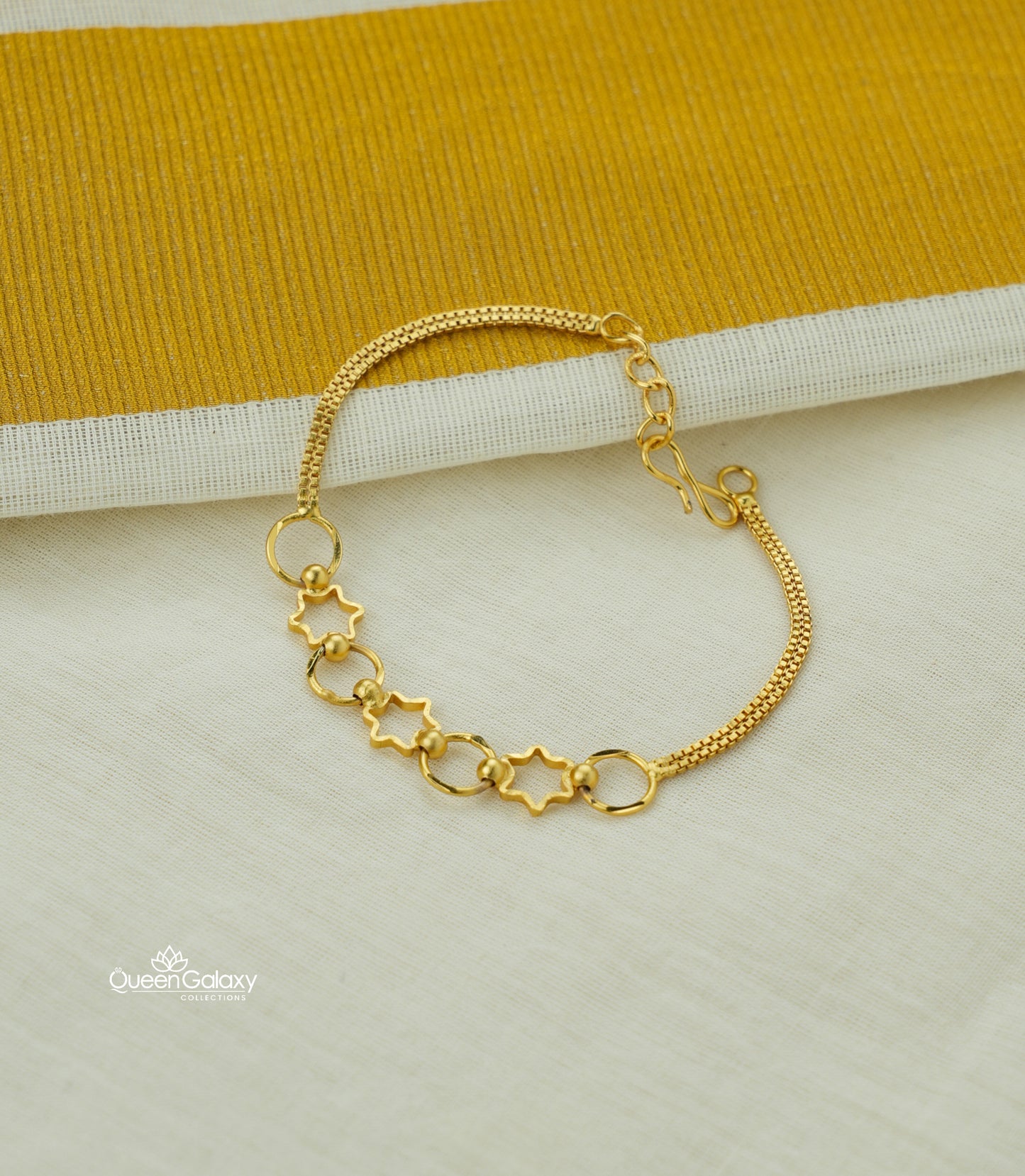 Gold plated bracelet with star shaped links on a light background- queen galaxy collection