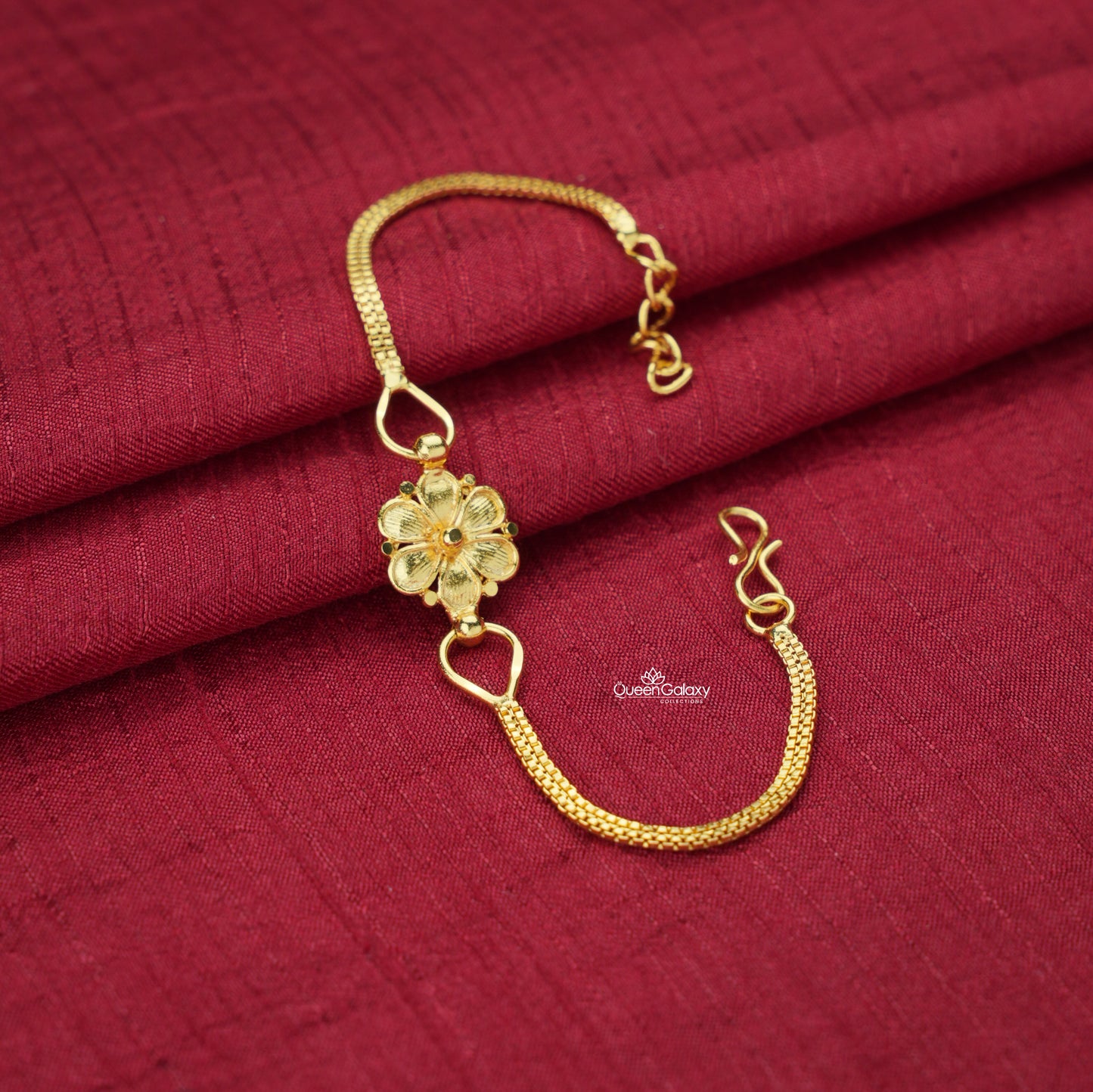 Gold plated bracelet with floral design on a red fabric background
