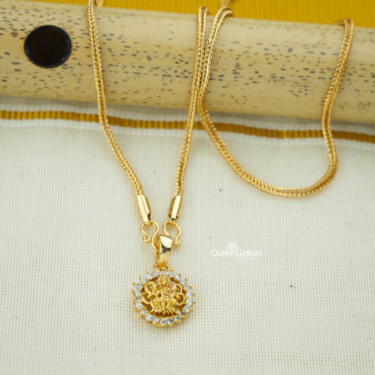 Gold-plated chain with AD stone Lakshmi pendant on a textured surface at queen galaxy collection