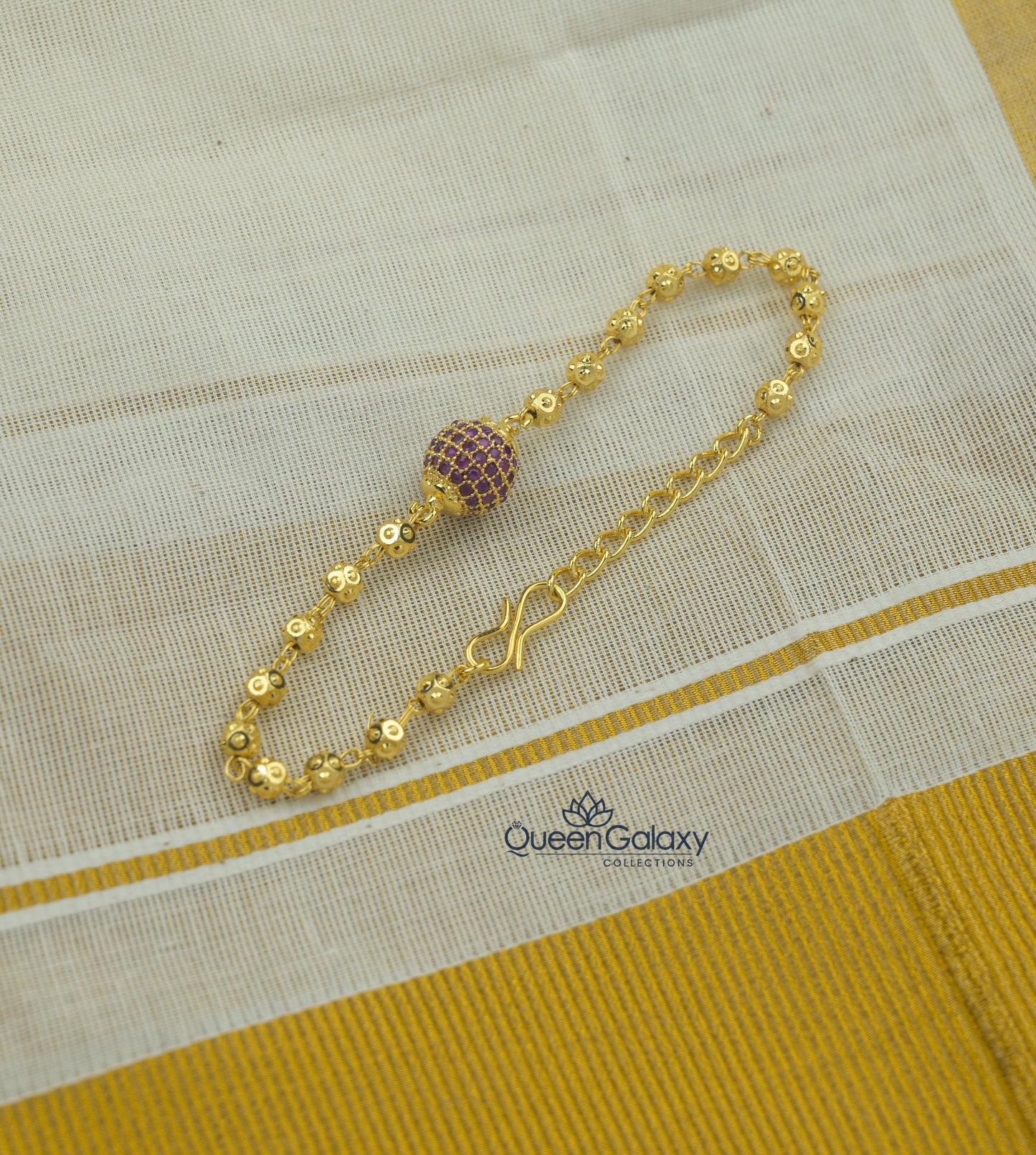 Gold Plated AD Stone Bracelet with Central Stone Ball laid out on a fabric, displaying its detailed design and clasp.