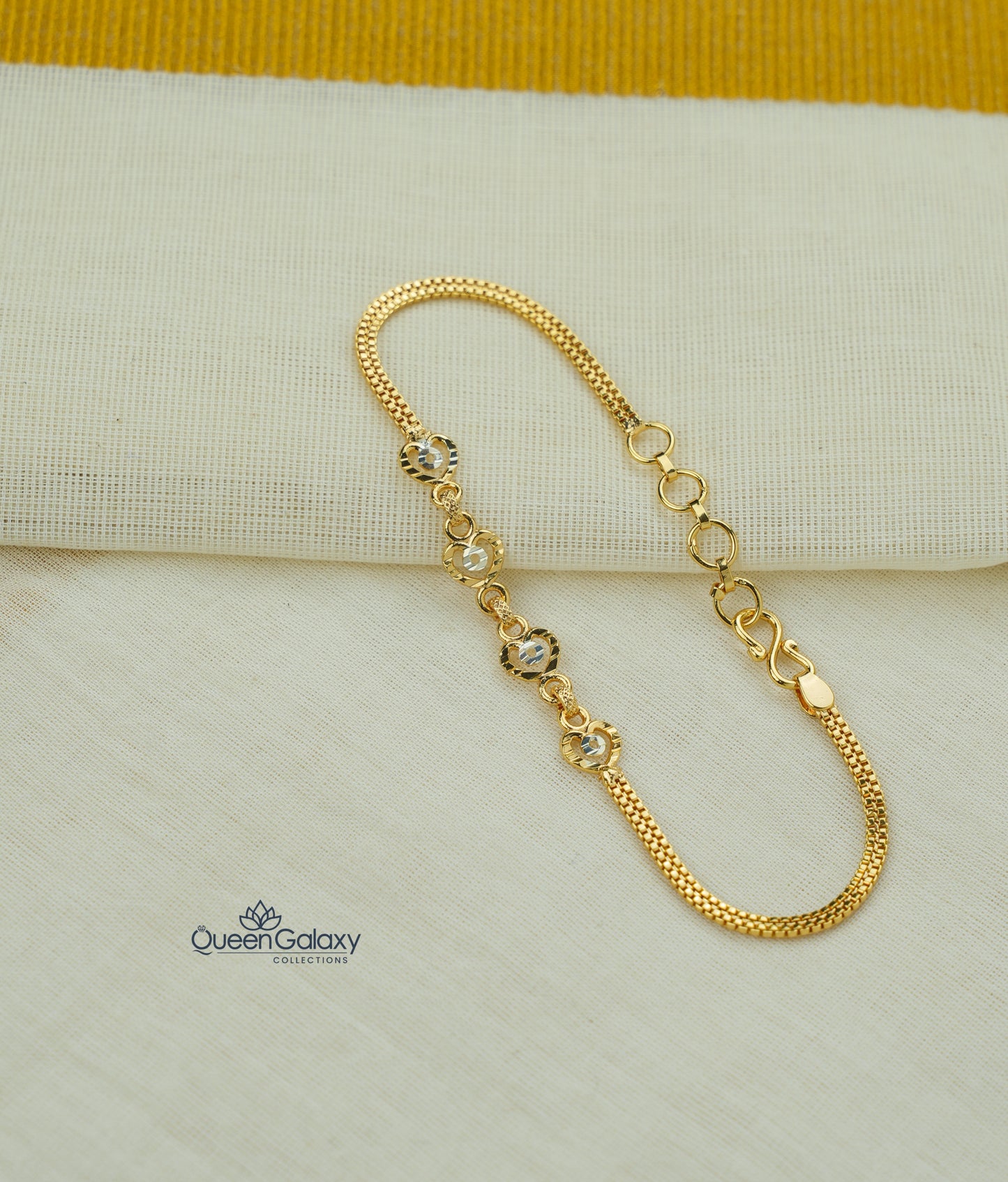 Gold bracelet with small crystals on a beige fabric background, featuring the Queen Galaxy brand.