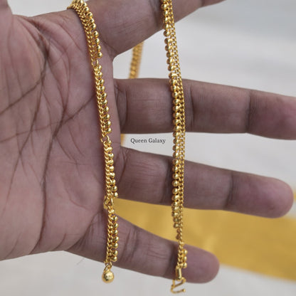 A gold-plated hip chain for babies held between fingers, displaying the chain's detail and length.
