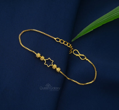Gold Plated Star Charm Bracelet for Women with star-shaped pendants laid out on a dark blue surface.