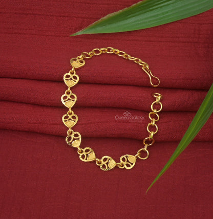 One Gram Gold Plated Heart Motif Bracelet with a link chain design displayed on a red fabric surface with a leaf beside it.