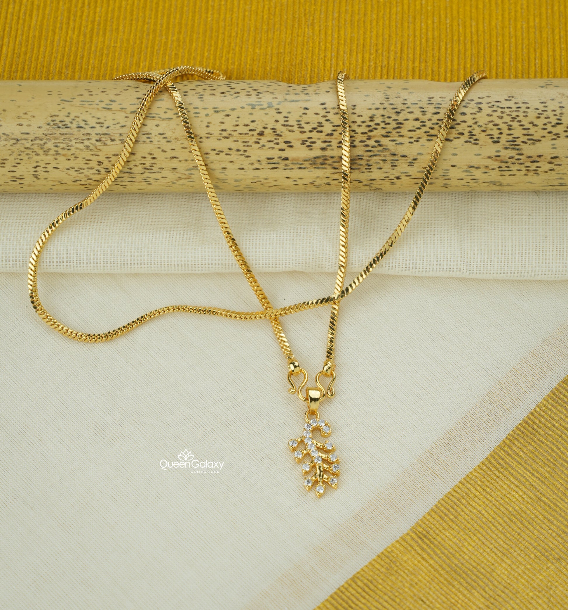 Gold plated chain with AD stone pendant placed on kasavu saree background - queen galaxy collection