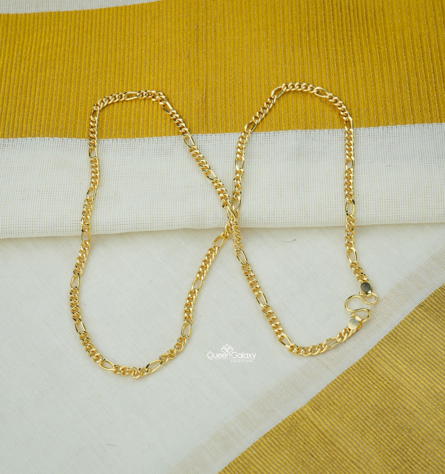 Gold plated Figaro chain displayed on Kerala kasavu saree background - queen galaxy collection