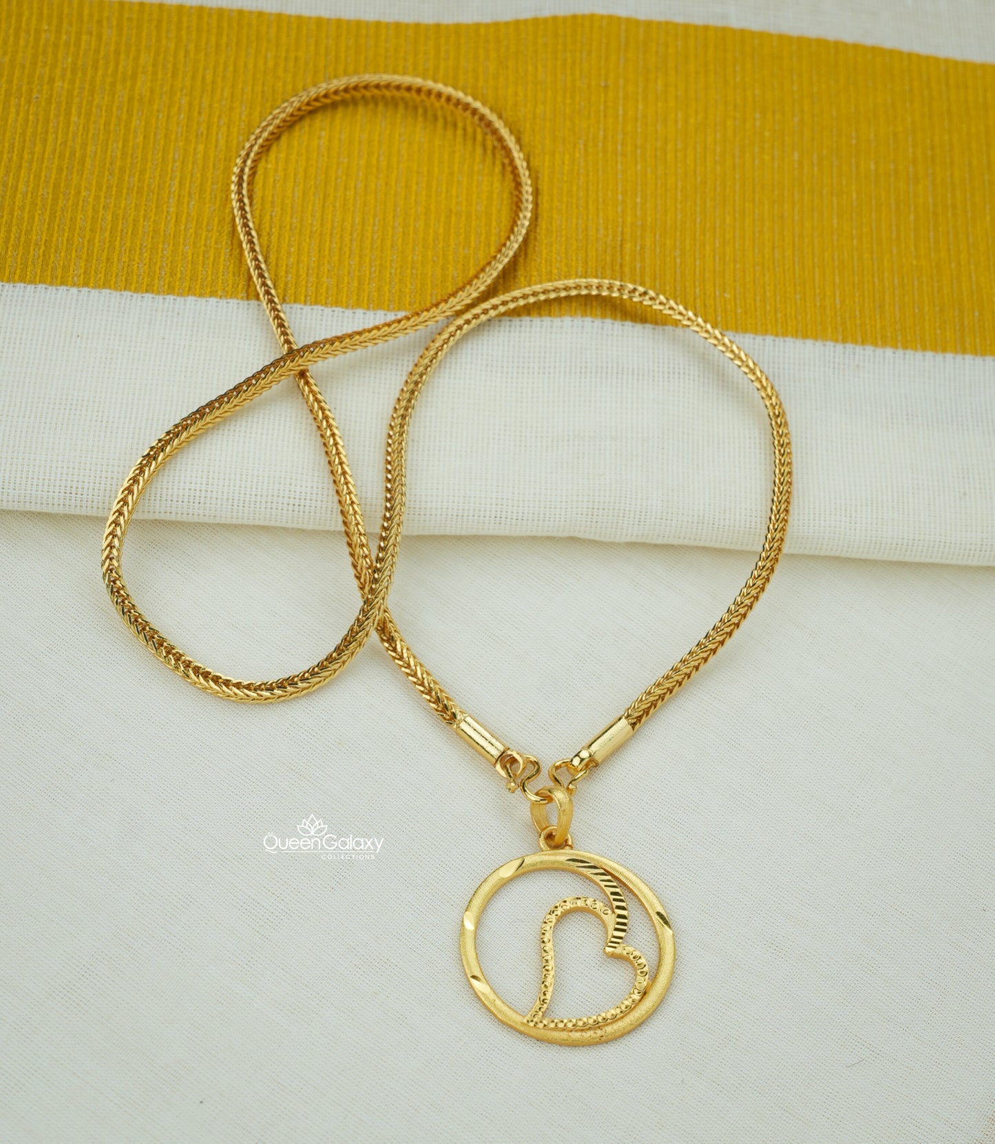 Gold plated chain with heart design pendant on cream and golden fabric background - queen galaxy collection