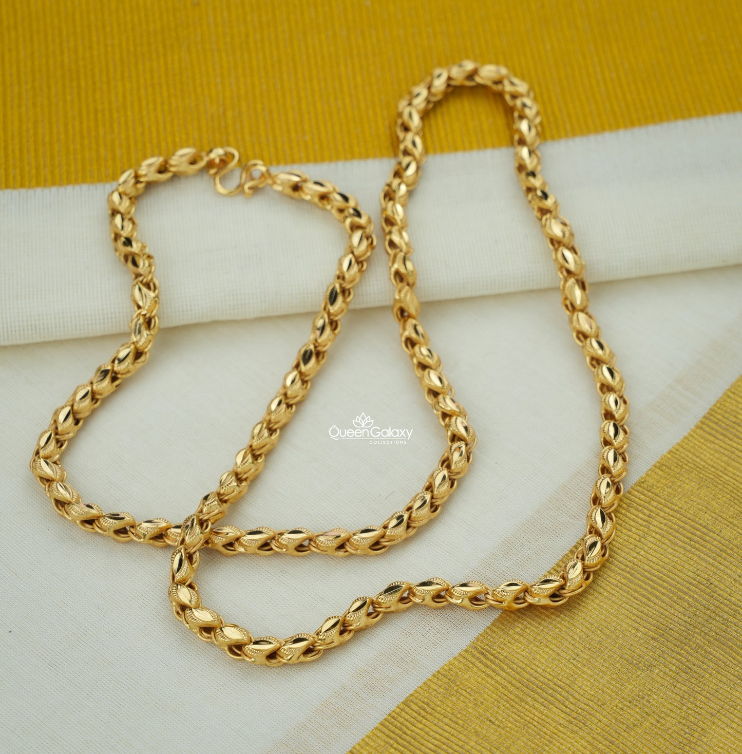 Gold plated twisted rope design chain on a white and yellow fabric background