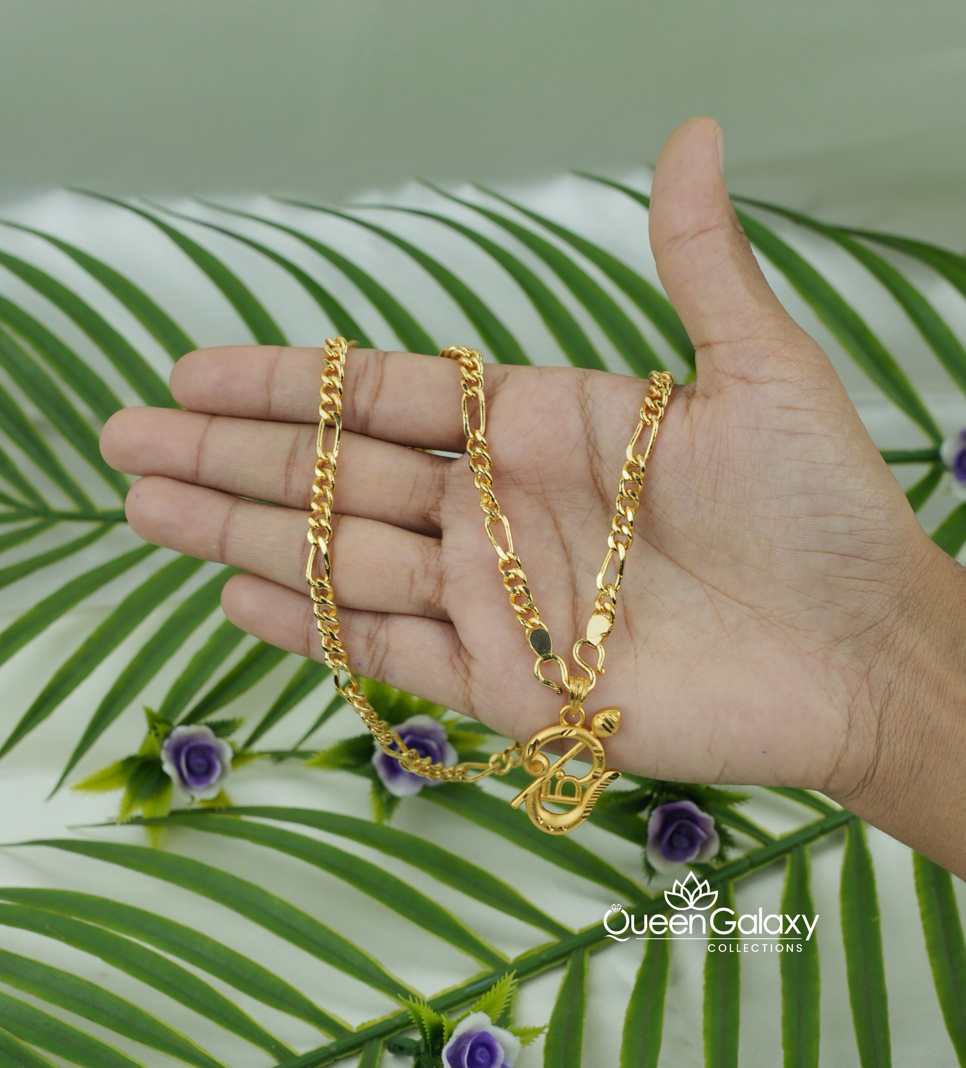 Gold Plated Sachin Chain with Murukan Vel Pendant held by a hand with a green leafy background