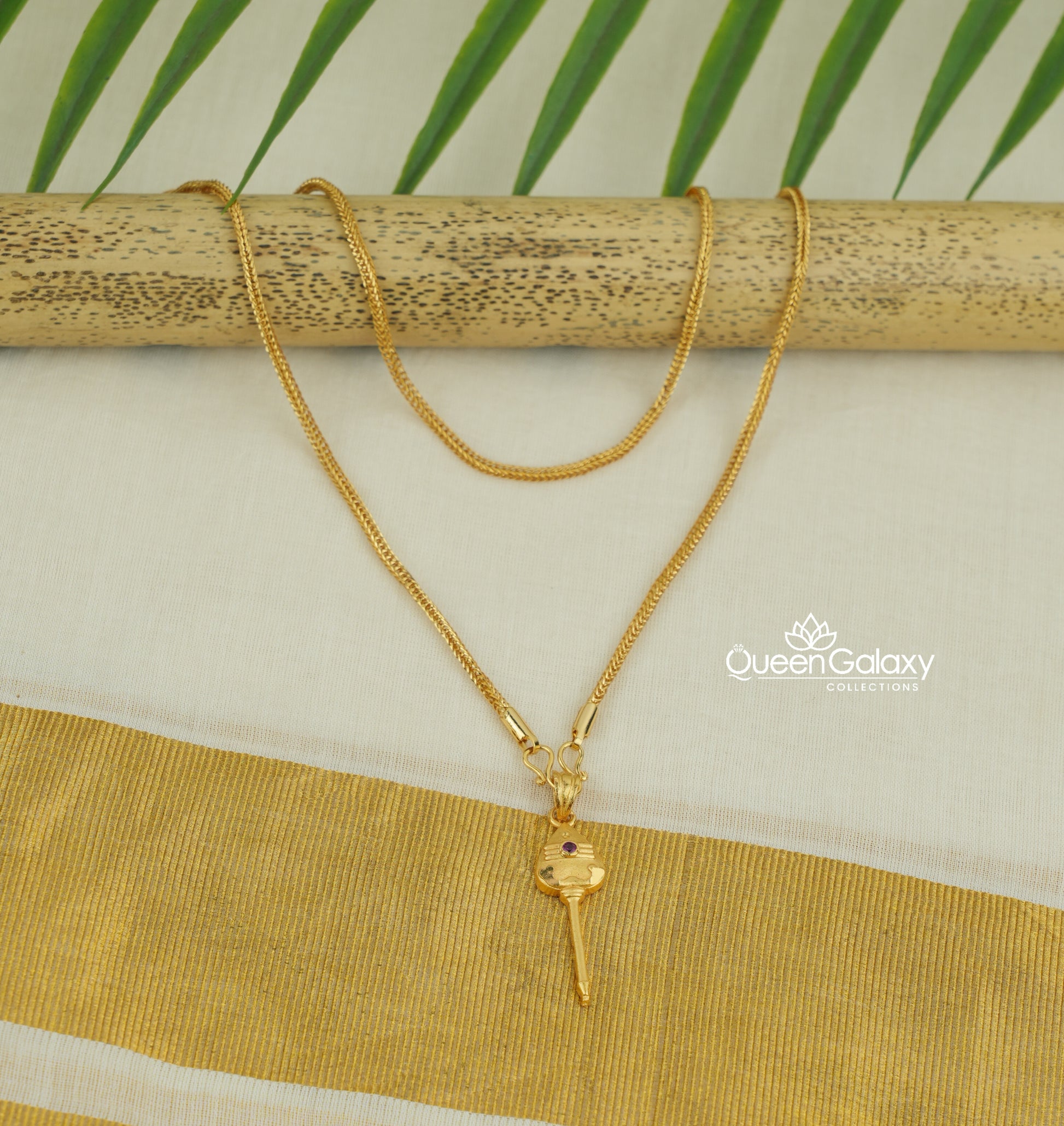 Gold plated box chain with murukan vel pendant on a wooden stick with a natural background - queen galaxy collection