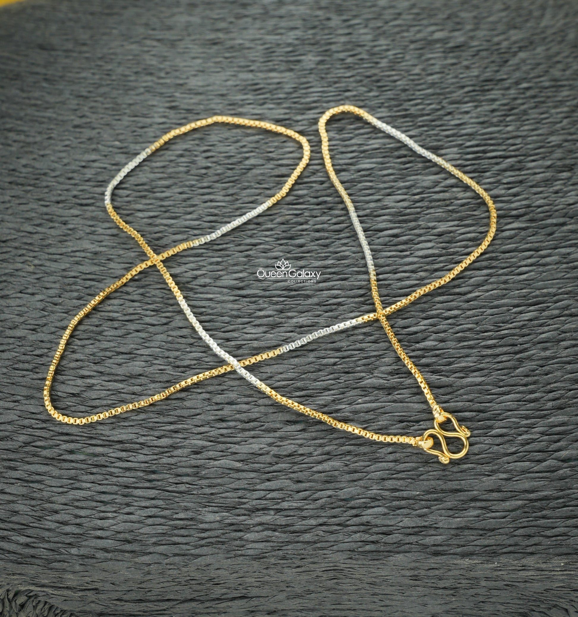white Gold plated chain with a clasp on a textured black surface