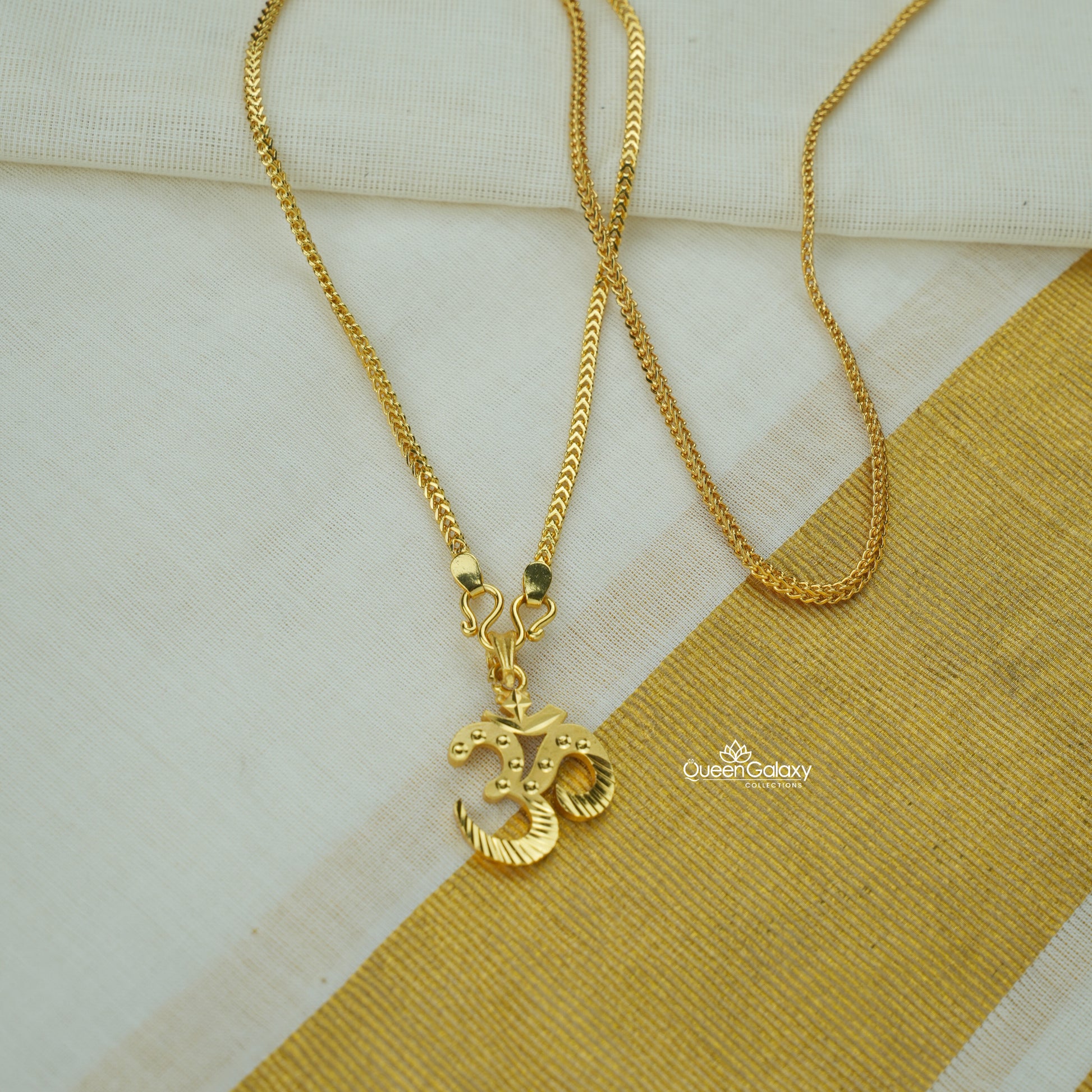 Gold plated chain with Om pendant on a striped fabric background