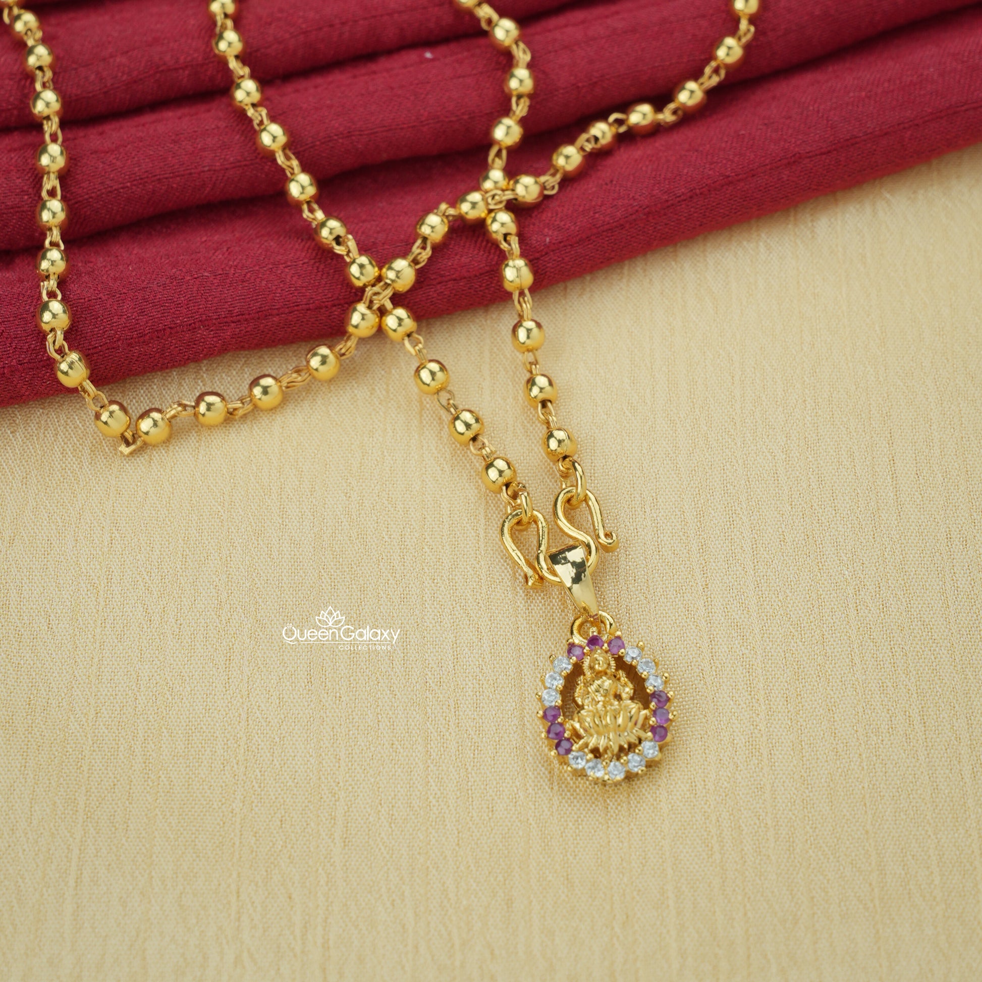 Gold plated beaded chain with AD stone Lakshmi pendant on a white surface