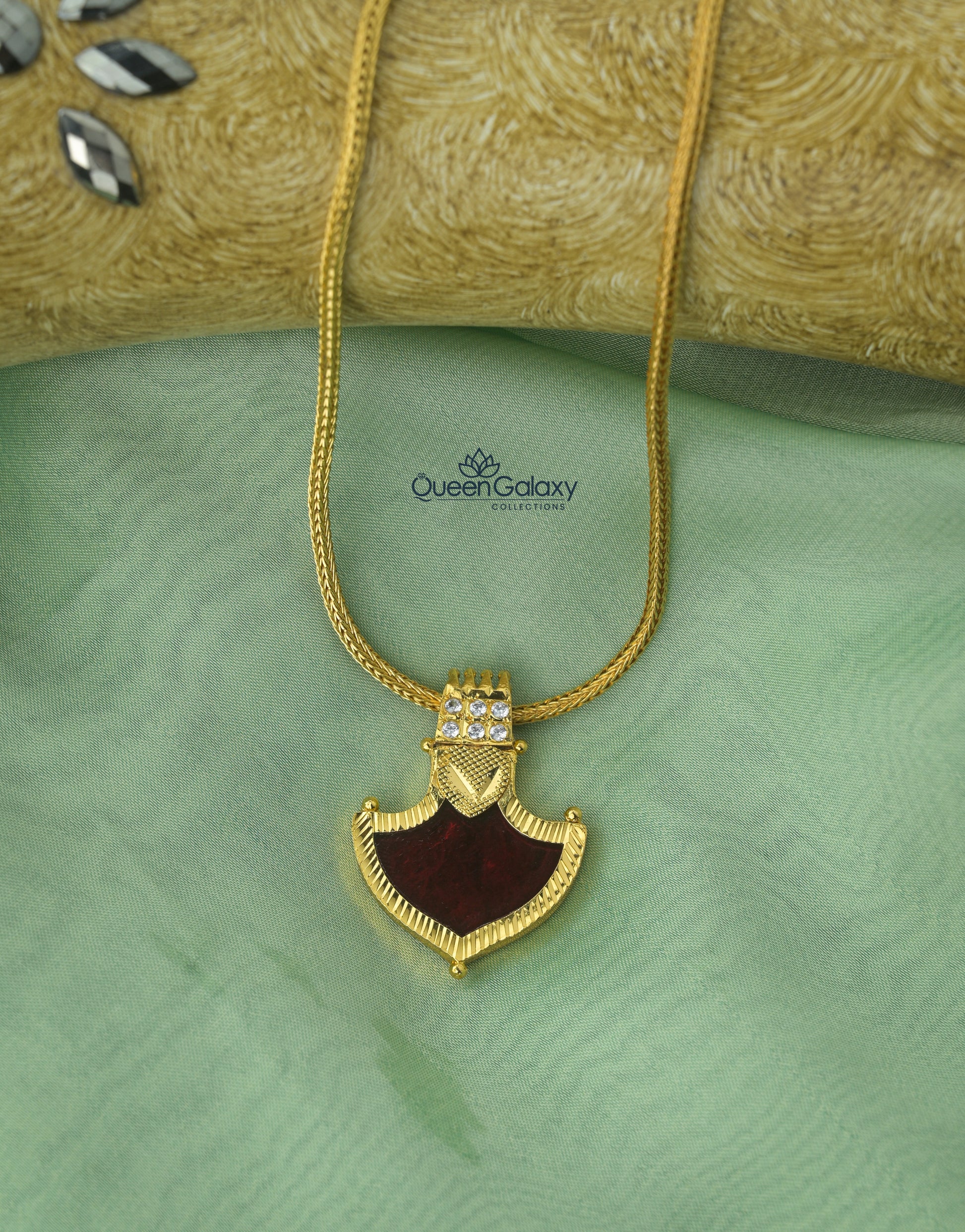 Gold plated Palakka pendant with maroon stone and white accents on gold chain