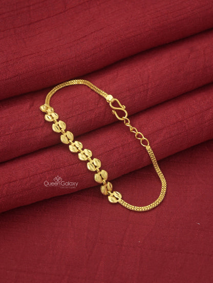 Gold Plated Leaf Motif Bracelet with a chain link design placed on a red fabric surface. queen galaxy collection