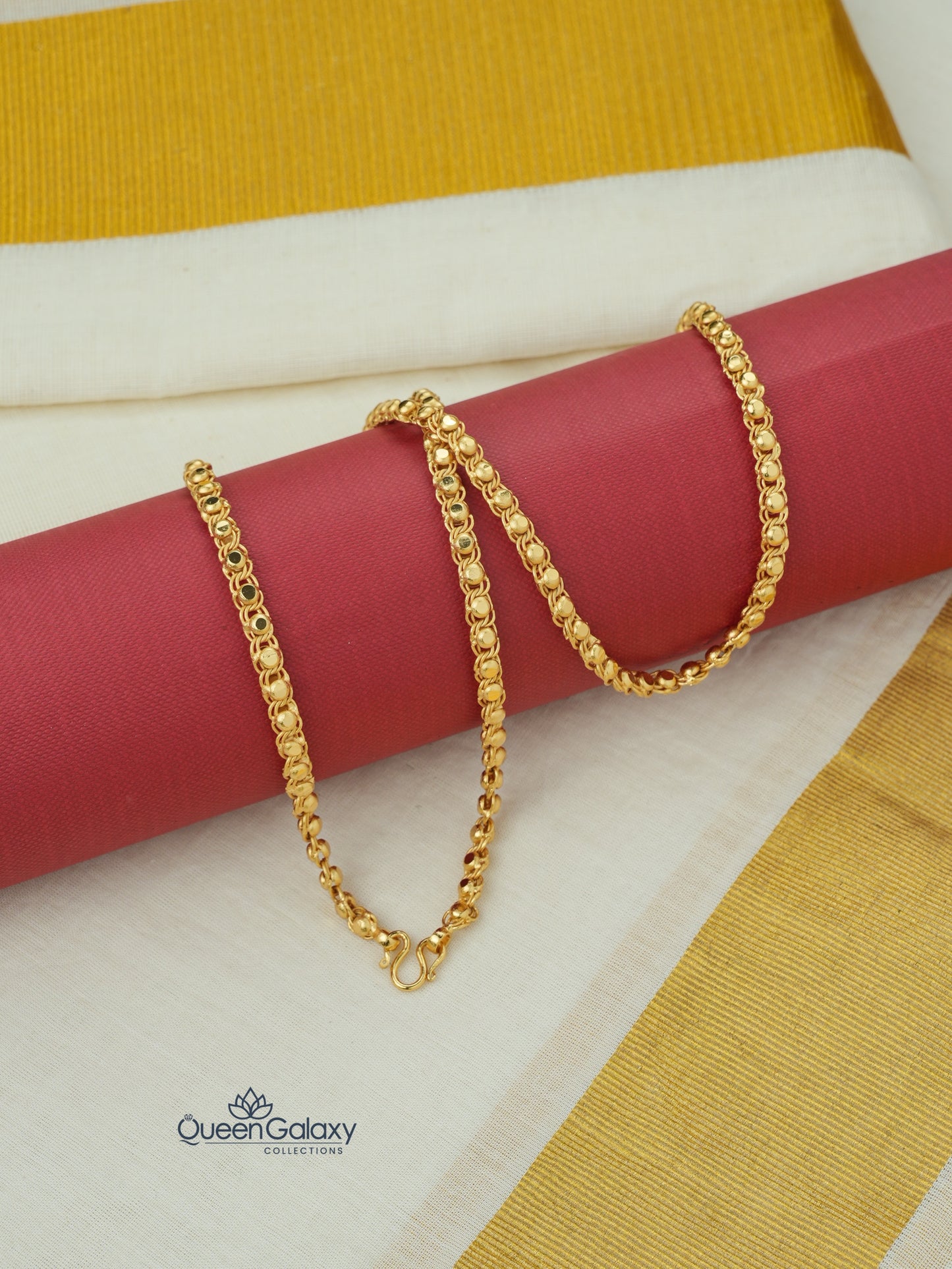 Gold plated designer chain placed on kasavu saree background with red roll - queen galaxy collection