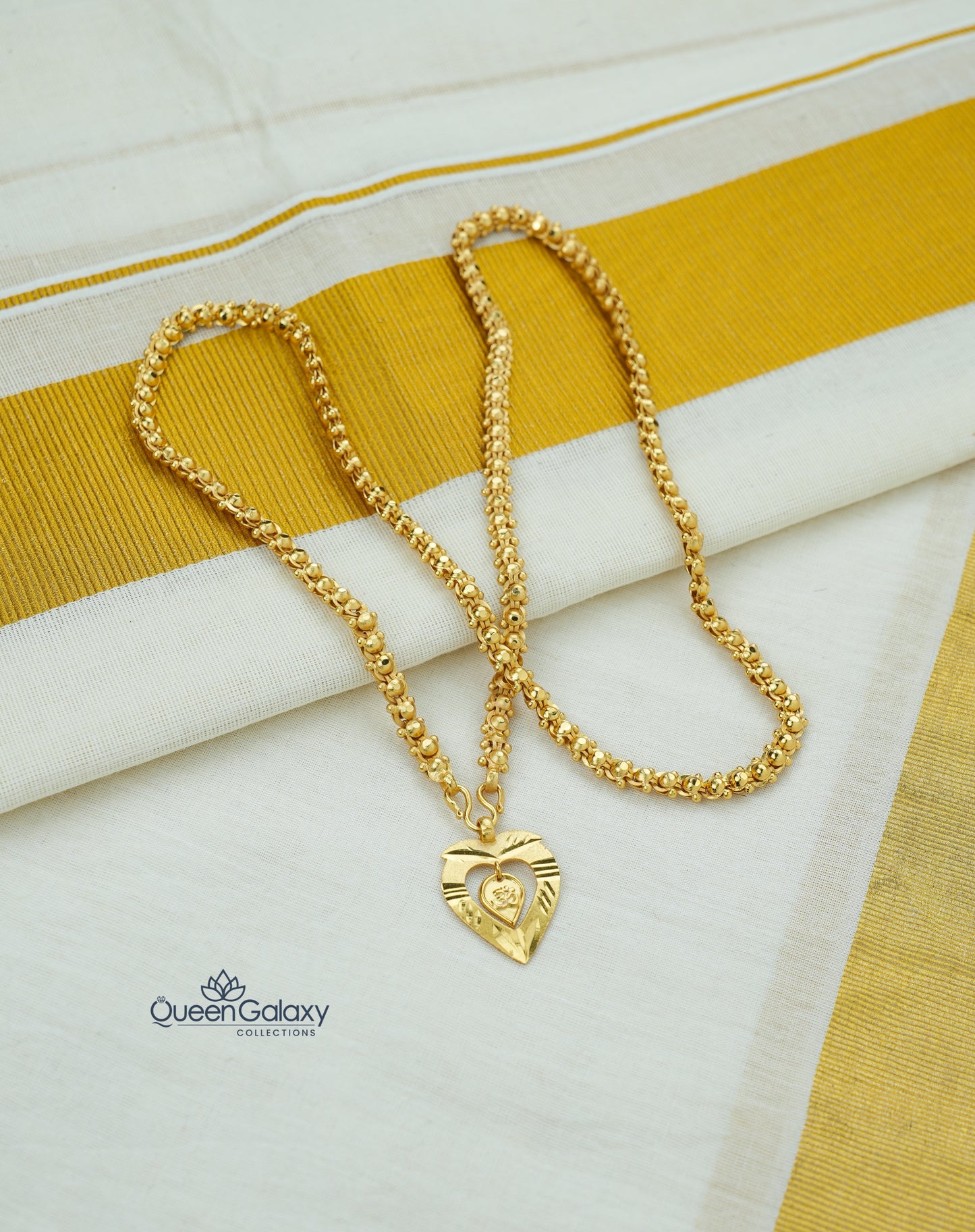 Gold plated bead chain with Om thali pendant on a white and yellow striped fabric background, featuring the Queen Galaxy brand.