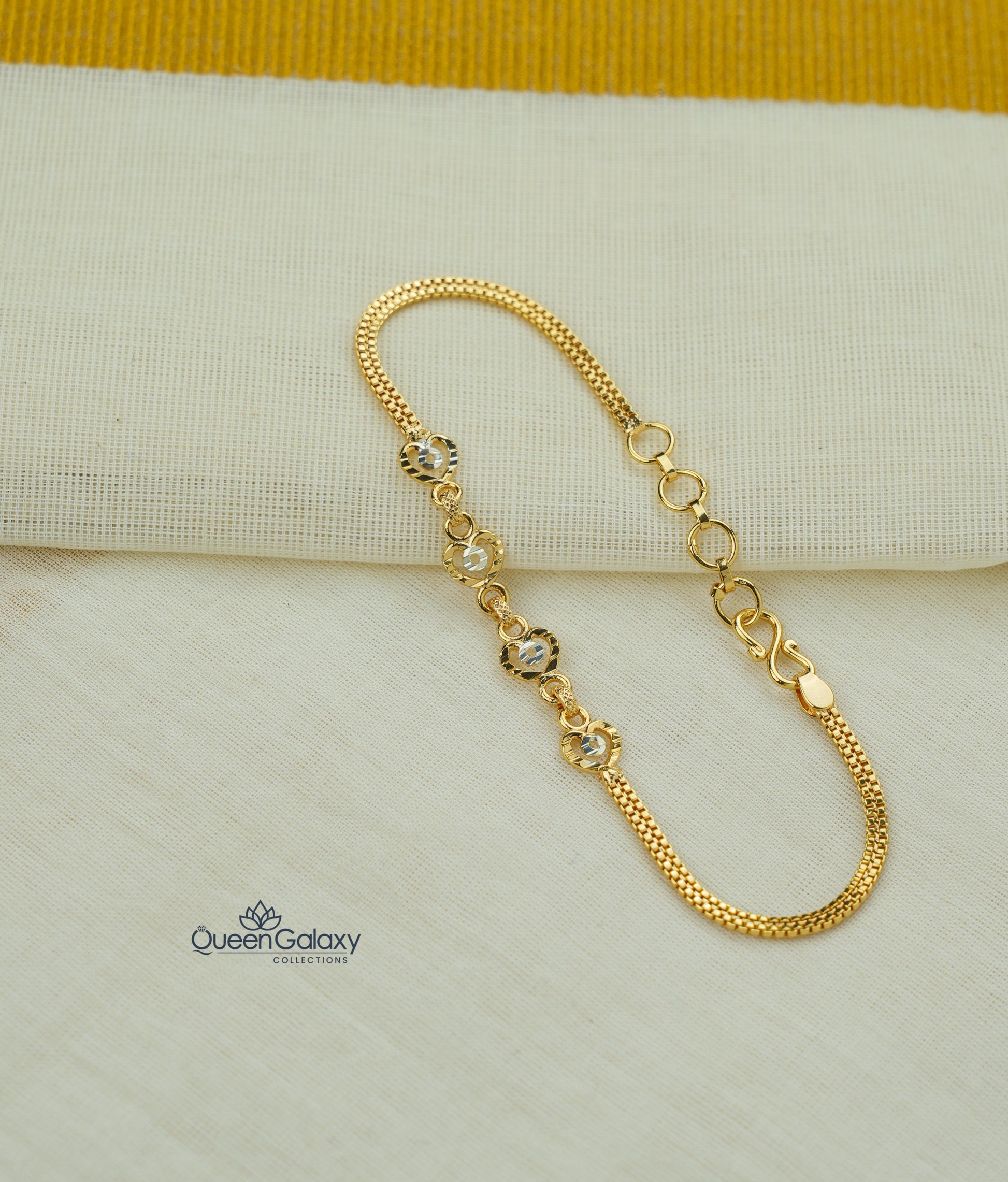 Gold bracelet with small crystals on a beige fabric background, featuring the Queen Galaxy brand.